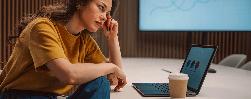 Imagem de uma pessoa analisando gráficos num notebook com cara de impaciência/preocuopação