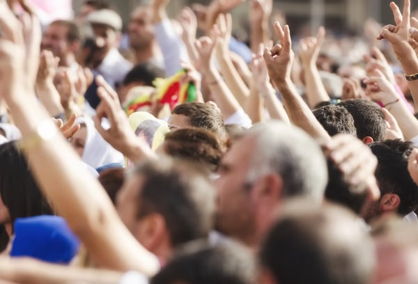 A imagem apresenta uma multidão com braços levantados em um comício político. O tema do artigo é curva de inovação.