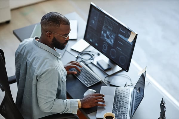 A imagem apresenta um homem jovem afro-americano trajando roupas formais e que está sentado em frente a um computador. O tema do artigo é empreendedorismo tecnológico.