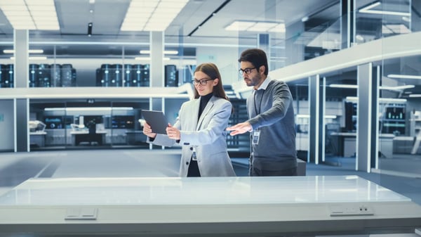 A imagem apresenta um homem e uma mulher jovens em um laboratório avaliando algo na tela de um tablet. O tema do artigo é gêmeos digitais.