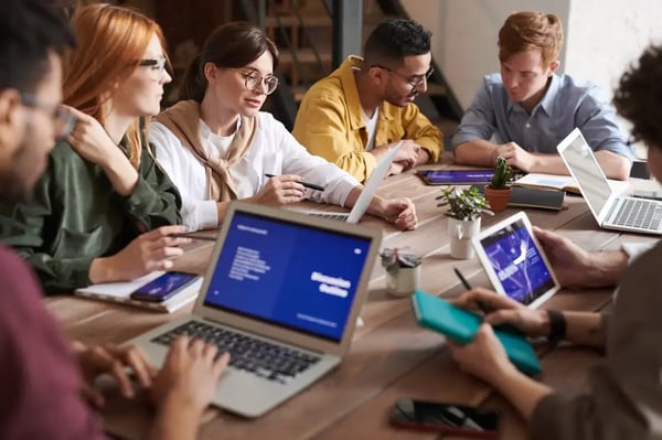 pessoas com computadores em uma mesa compartilhada de trabalho