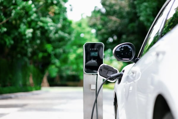 A imagem apresenta um ponto de abastecimento para carros elétricos, sendo que um carro elétrico está sendo recarregado. O tema do artigo é mobilidade inteligente.