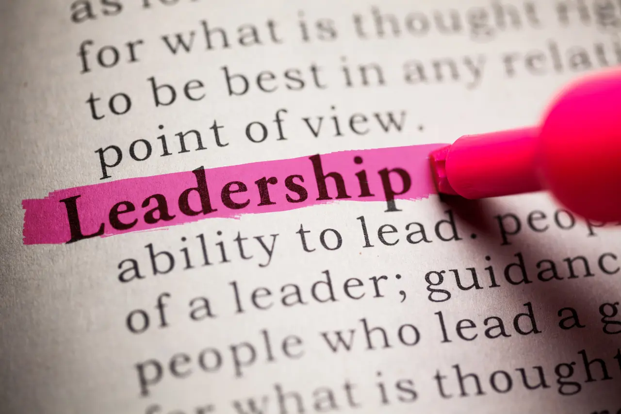 A imagem traz um marca-texto destacando em cor-de-rosa a palavra liderança, escrita em inglês em um livro. O tema do artigo é 10 livros sobre liderança para ler este ano.